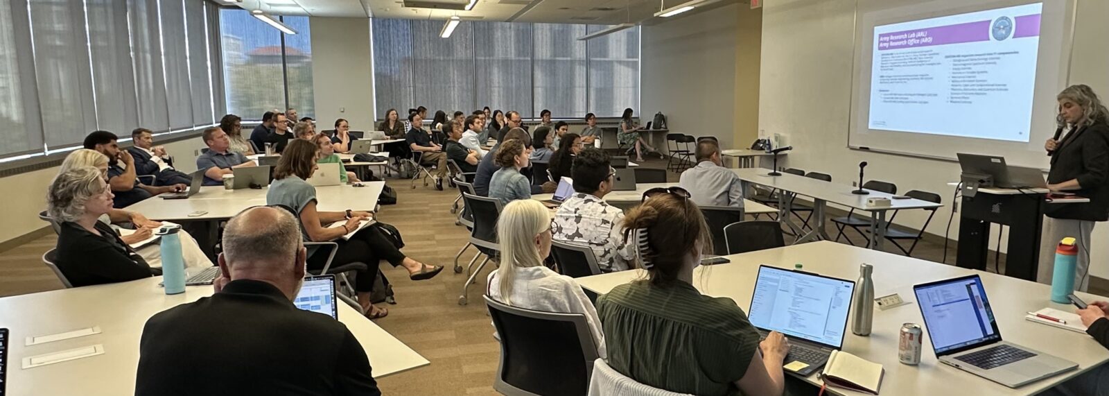 Faculty and staff attend a Department of Defense funding briefing in a UW–Madison classroom, with a slide on the Army Research Laboratory and Army Research Office projected at the front.