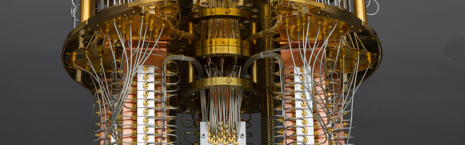 Close-up of a superconducting quantum computer's gold-plated cryogenic stages, copper columns, and coaxial wiring inside a dilution refrigerator.