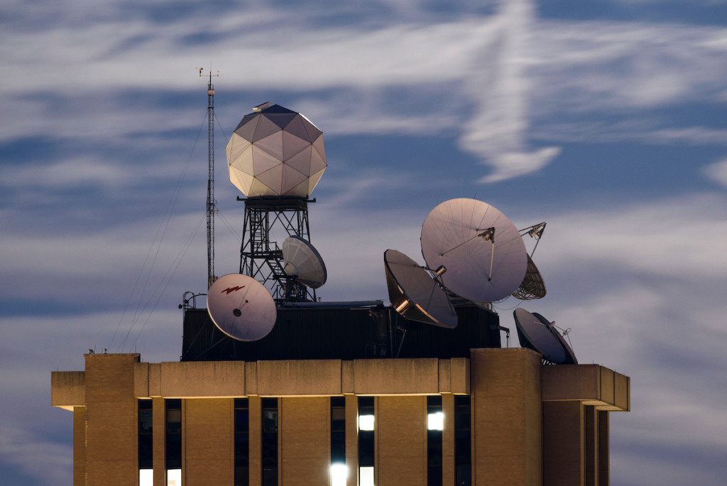 Satellite dishes and a geodesic radar dome on the roof of the UW–Madison Atmospheric, Oceanic and Space Sciences building against a streaked evening sky.