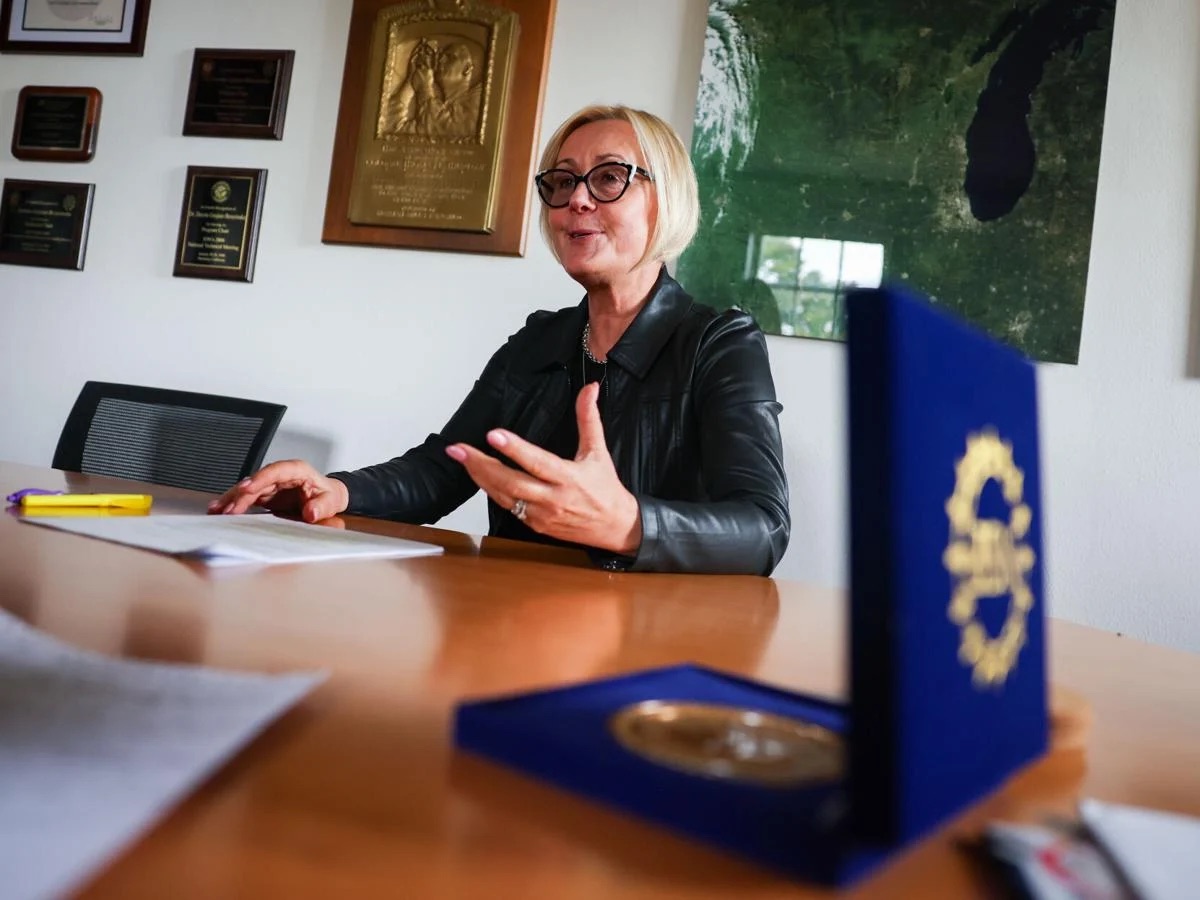 Vice Chancellor for Research Dorota Grejner-Brzezińska speaking at a conference table in her office, with an award medal in an open case in the foreground.