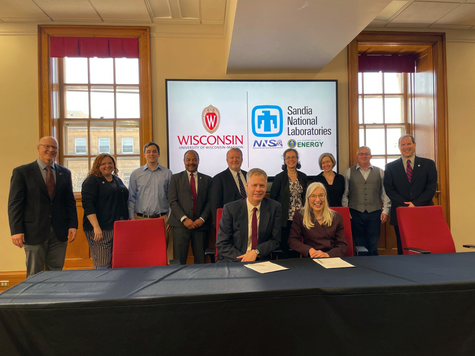 Officials from UW–Madison and Sandia National Labs standing in a Bascom Hall conference room.